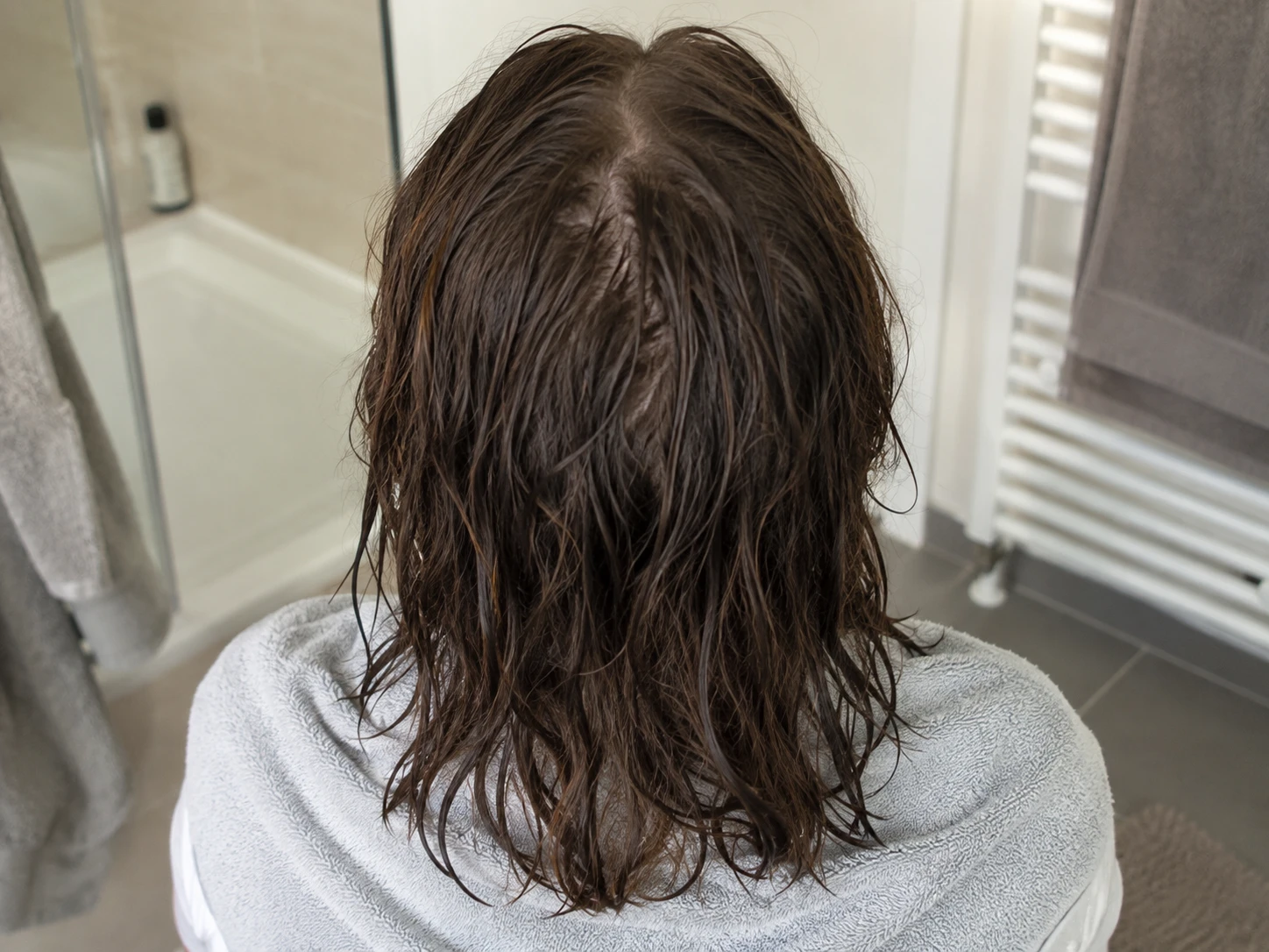 Rear view of naturally damp brown hair above a cotton towel