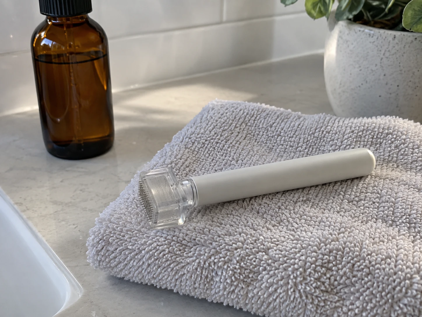 A dermastamp on a folded white towel beside a closed amber bottle